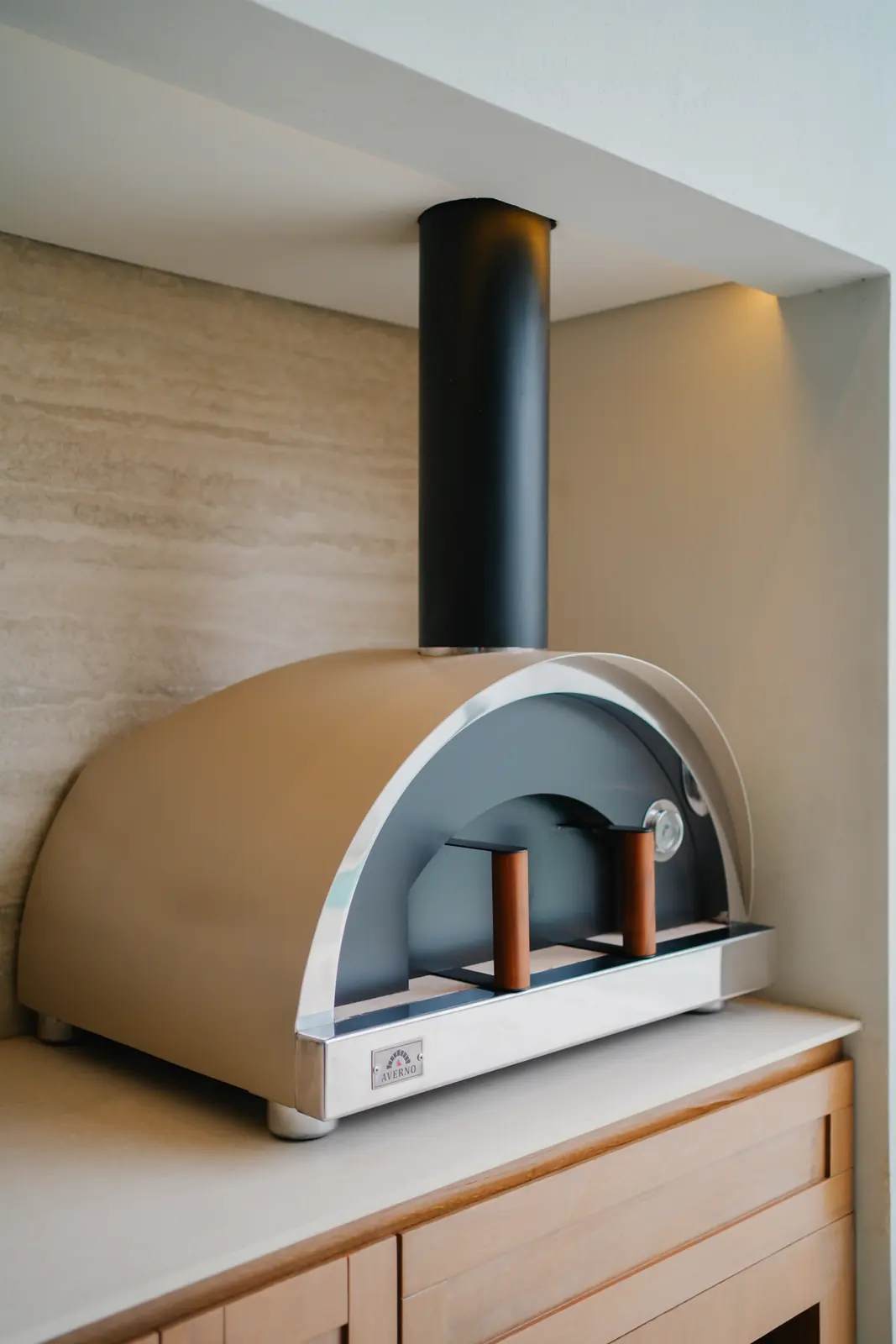 Horno Averno color arena con chimenea negra sobre una mesada