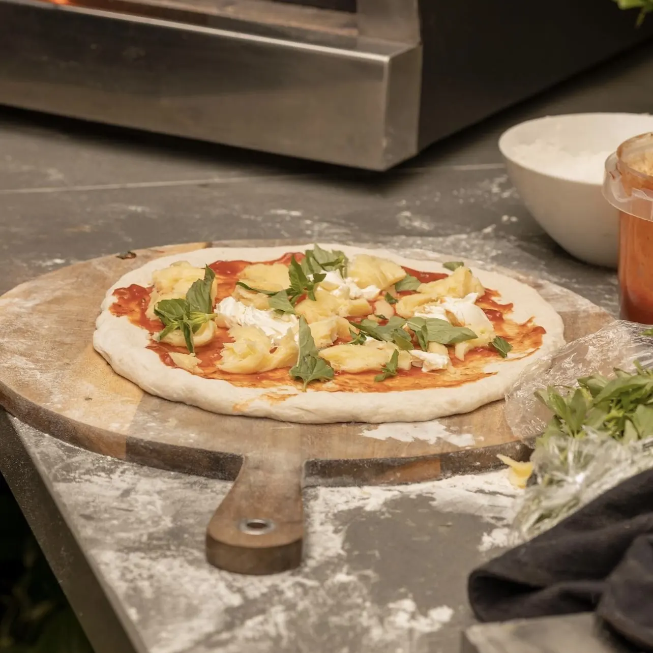 Pizza lista para entrar al horno Averno, sobre una tabla de madera