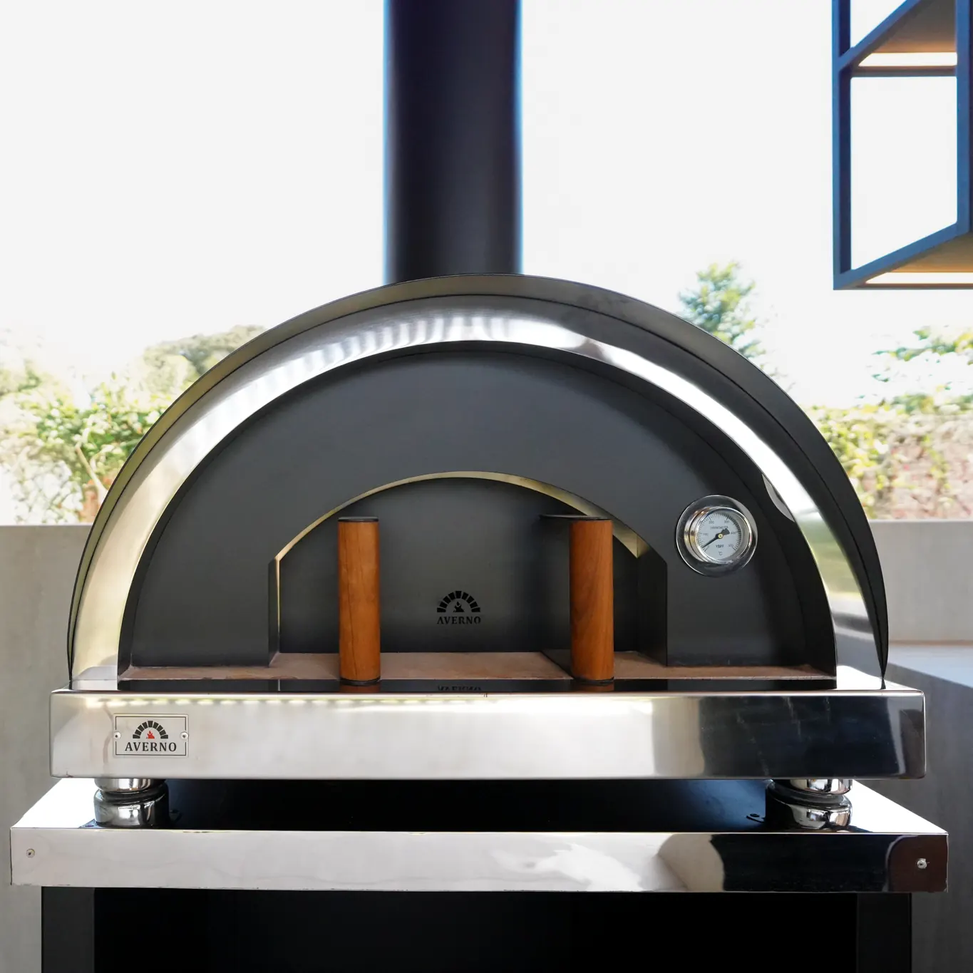 Frente del horno Averno Firenze XL con termómetro, manijas de madera y la placa de la marca, sobre su base de acero