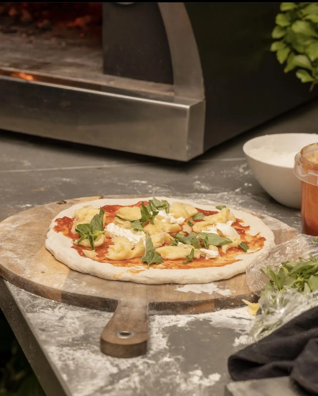Pizza lista para entrar al horno Averno, sobre una tabla de madera