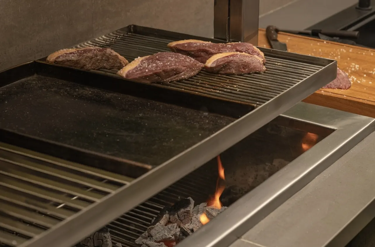 Carne a la parrilla sobre una churrasquera Averno con brasas encendidas