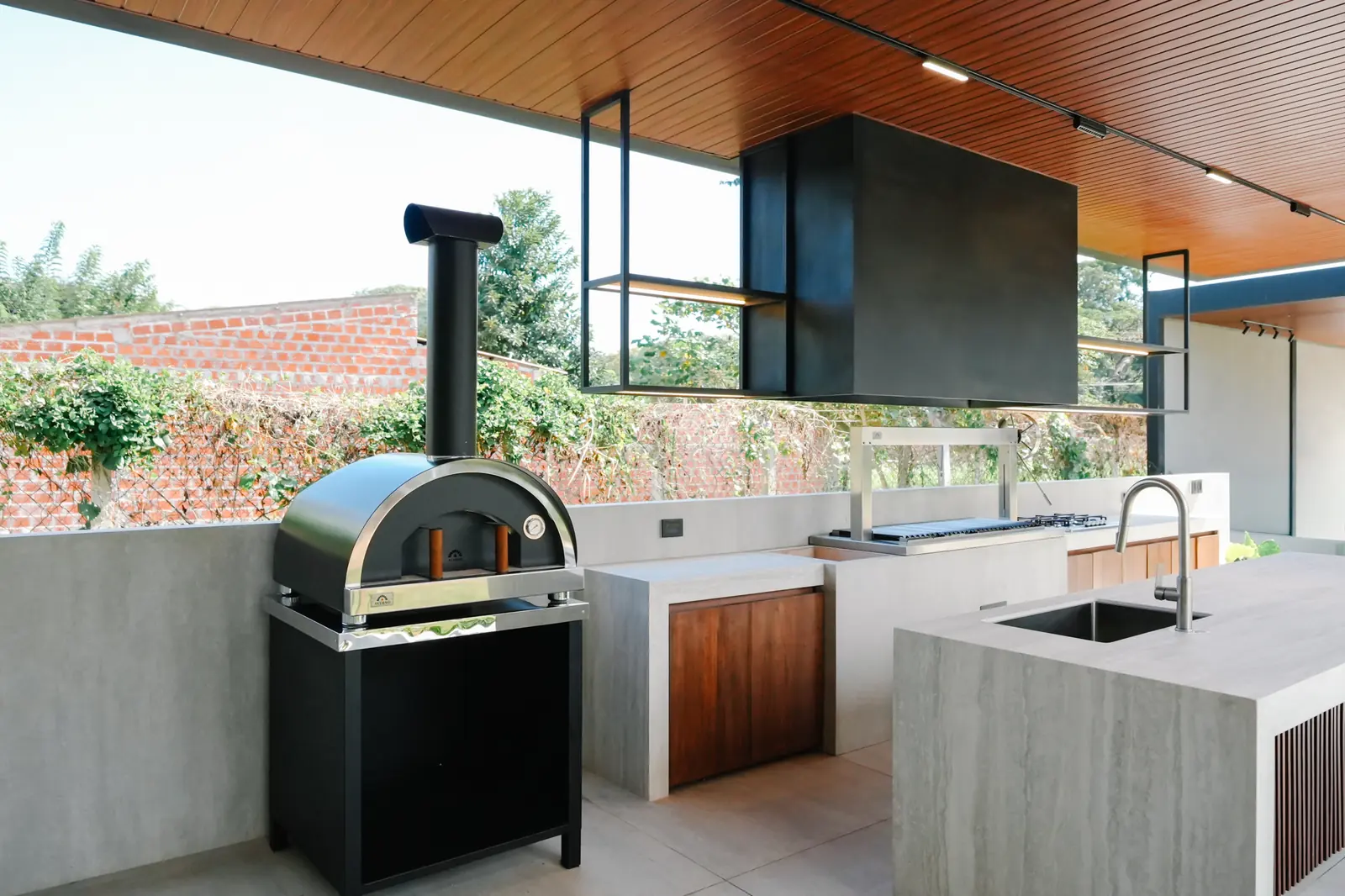 Horno Averno negro con chimenea junto a la mesada con pileta de la Quinta Porongo