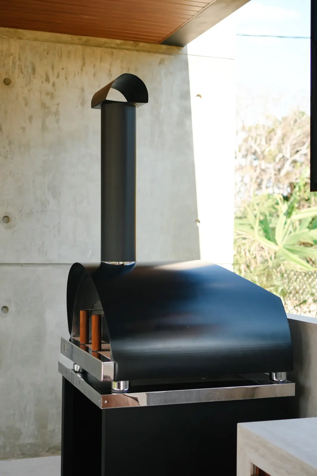 Detalle del horno Averno negro con chimenea de acero sobre su base, en la Quinta Porongo