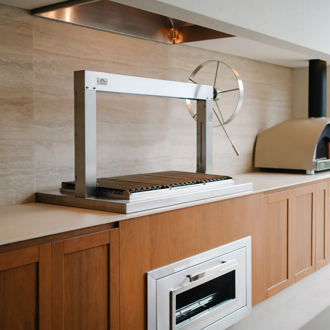 Churrasquera Averno Standard junto a un horno color arena y un mueble de madera