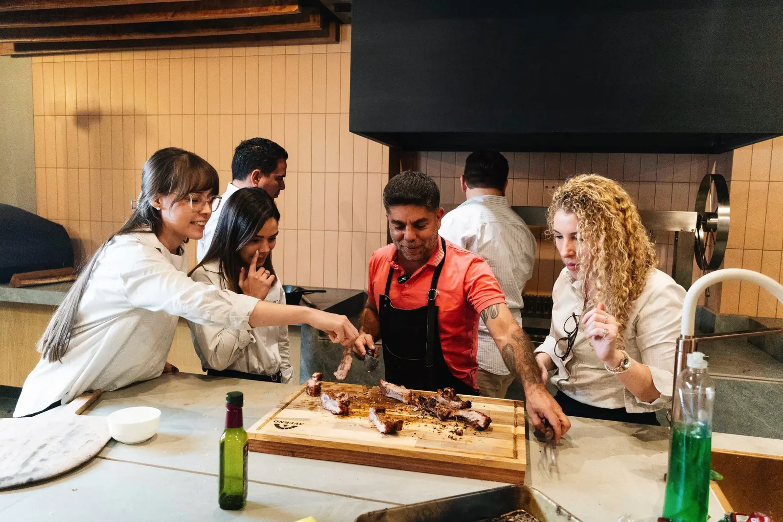Demostración de cocina en el Showroom Tumpar: un grupo reunido en torno a una tabla de carnes frente a la churrasquera