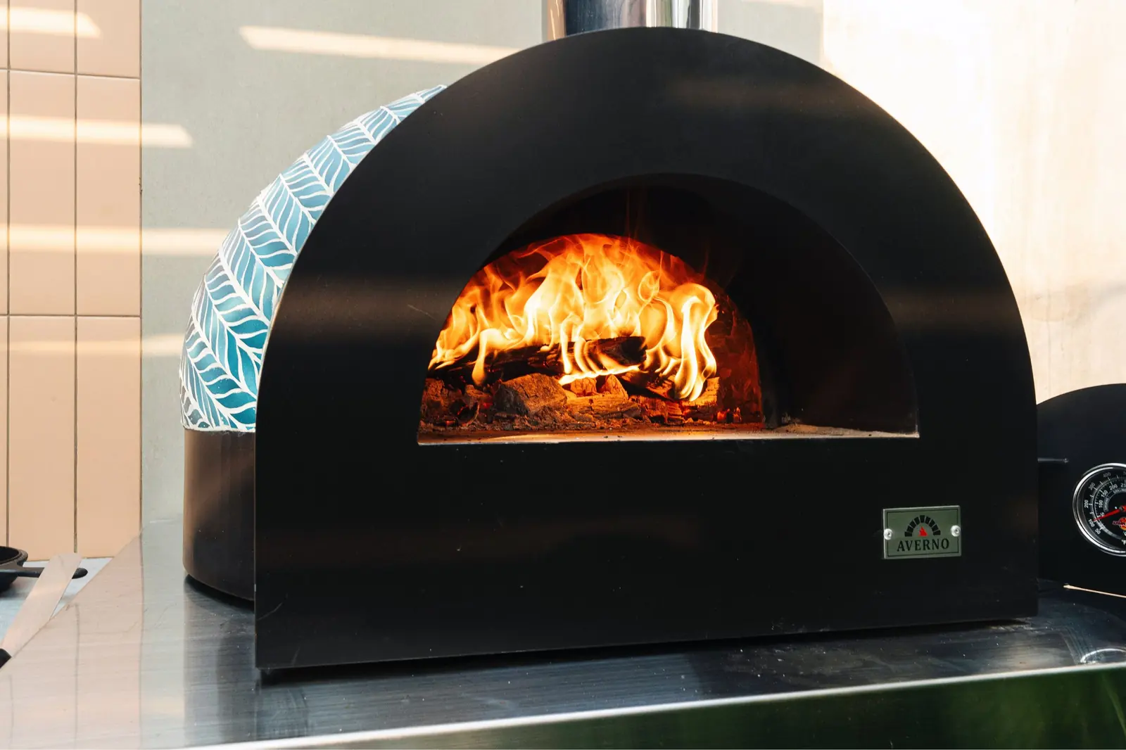Horno Averno negro con la leña encendida en el Showroom Tumpar